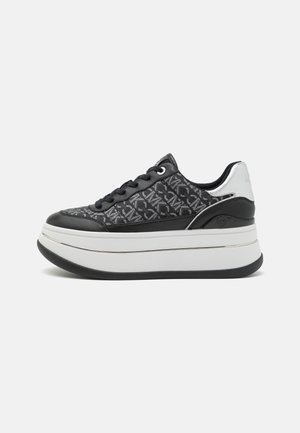 Svarta sneakers med en texturerad ovandel, silverdetaljer och en kraftig vit platt sula. Har snörning och runda öglor för fäste.