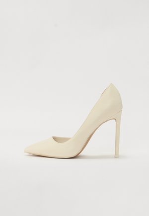 Sapato de salto alto de bico fino em creme, feito de couro suave, com um salto stiletto fino e um leve detalhe recortado nas laterais.