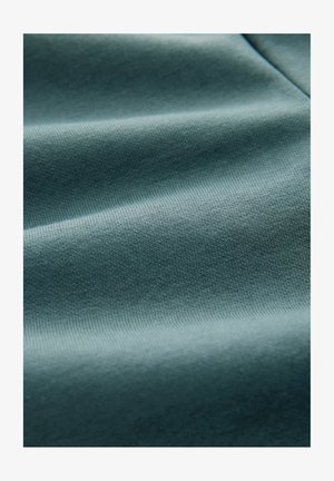 Blød, struktureret stof i en dæmpet teal farve, der har en glat overflade med subtil stræk og et ensartet ribbet mønster gennem hele stoffet.