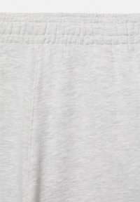 Lysegråt stof med elastisk linning og synlig søm, sandsynligvis del af bløde casual- eller sportbukser.