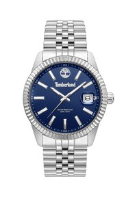 Orologio in acciaio inossidabile con quadrante blu, indicatori delle ore argentati e display della data. La lunetta è texturizzata, con un braccialetto in metallo intrecciato. Resistente all'acqua fino a 50 metri.