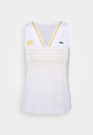 Biały tenisowy top na ramiączkach z dekoltem w serek, złotymi paskami na ramionach, logo Roland Garros na lewej piersi oraz zielonym krokodylem Lacoste po prawej stronie.