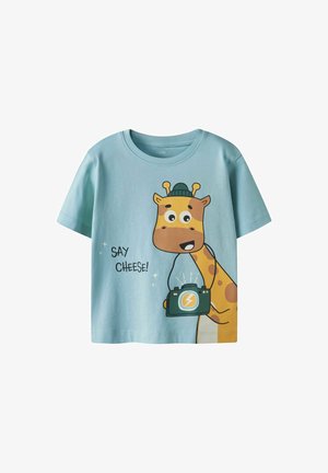 Camiseta infantil de color azul claro hecha de algodón, que presenta un gráfico de una jirafa de dibujos animados sosteniendo una cámara, con el texto "¡Diga Queso!" impreso al lado.