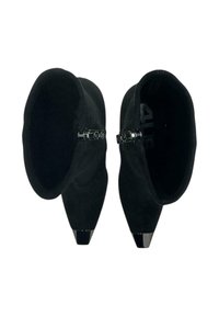 Stivaletti neri alla caviglia con una morbida texture in camoscio, punta appuntita e un accento metallico nero lucido nella parte anteriore. Design liscio ed elegante senza lacci visibili.