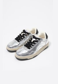 Silver sneakers with cracked texture, black laces, and a beige sole. Features a black heel cap and a padded tongue for comfort.