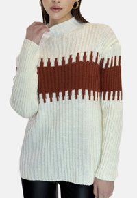 Strikket sweater i cremefarve med en horisontal rustfarvet stribe, der har en ribbet struktur og høj hals. Lange ærmer med tætsiddende manchetter.