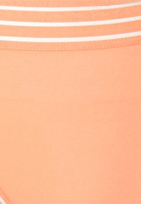 Peach-colored fabric with a smooth texture, featuring white horizontal stripes on the waistband. Simple design, no visible embellishments.