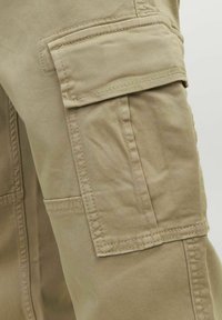 Pantalons cargo de couleur kaki avec une grande poche latérale dotée d'un rabat et de coutures visibles sur la jambe.