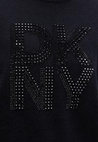 Maglione nero con grandi lettere in strass che formano la scritta "DKNY." Il tessuto ha una finitura strutturata con collo rotondo.