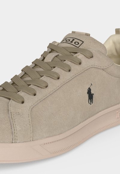 Μπεζ σουέτ αθλητικό παπούτσι με κορδόνια στο ίδιο χρώμα, μαύρο λογότυπο Polo στο πλάι και ελαστική σόλα με διακριτικό μοτίβο.