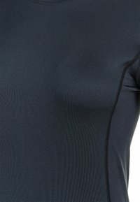 Donkerblauw sportshirt met een gladde textuur, met platte naden langs de zijkanten en een ronde halslijn.