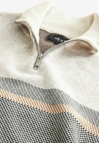 Maglione a maglia beige con colletto zip, caratterizzato da strisce grigie e arancioni e da un motivo a scacchi. Dettaglio della zip argentata sul collo.