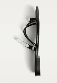 Svart flip-flop med en elegant design och glänsande finish. De mjuka remmarna har en texturell kontrast med en vit accentdel.