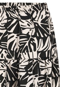 Schwarz-weißer Rock mit einem abstrakten Blättermuster, strukturiertem Stoff, gestuftem Design und einem elastischen Bund für einen bequemen Sitz.