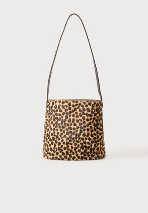 Sac à bandoulière avec motif léopard et fine sangle noire sur fond neutre.