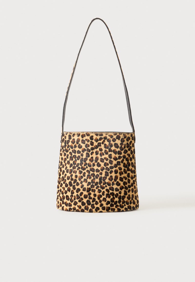 Sac à bandoulière avec motif léopard et fine sangle noire sur fond neutre.