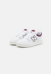White leather sneakers with a perforated toe box, maroon accents, and a prominent "N" logo on the side. Rubber sole for traction.