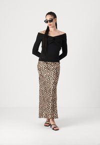 Crna majica bez naramenica s naboranim prednjim dijelom, u kombinaciji s dugom suknjom s leopard uzorkom i crnim sandalama na remenčiće.
