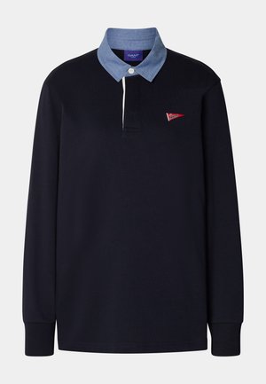 Navy long-sleeve polo shirt with a light blue chambray collar, featuring a red logo detail and a three-button placket. Cotton material.