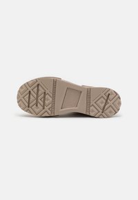 Sohle eines beigen Schuhs mit geometrischem Profilmuster und rechteckigen Rillen, in der Mitte steht der Markenname "Converse All Star".