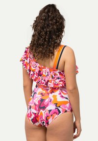 Yhdistelemällä kirkkaan vaaleanpunaisia, oransseja ja mustia kukkakuoseja varustettu yhden palan uimapuku. Varustettu röyhelöillä olkaimilla ja erottuvilla hihnoilla. Silkkinen kangas.