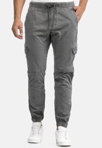 Gray cargo pants with elastic cuffs, drawstring waistband, and multiple pockets. Made from a soft, textured fabric with a relaxed fit.