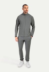 Gray athletic tracksuit made of smooth, stretchy fabric. Features a zippered jacket, elastic cuffs, and matching tapered pants.