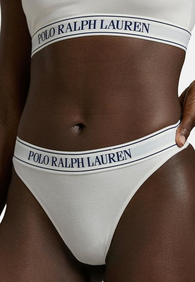 Valkoinen ribbineulottu puuvillahousu, jossa on tummansininen joustava vyötärönauha, "POLO RALPH LAUREN" -logo ja kontrastiväriset raidat.