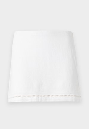 Λευκή μίνι φούστα από λινό με ευθεία τελειώματα και διακριτικές διακοσμητικές ραφές κοντά στο κάτω άκρο, παρουσιασμένη σε απλό φόντο.