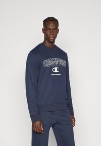 Φούτερ σε ναυτικό μπλε με λογότυπο «CHAMPION» σε αντίθετο λευκό, από μείγμα βαμβακιού, στρογγυλή λαιμόκοψη και ριμπ τελείωμα στα μανίκια και στο κάτω μέρος.