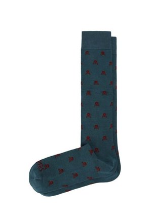 Par de calcetines largos hasta la rodilla de color verde azulado oscuro con un pequeño patrón de calaveras y huesos cruzados rojos por todas partes.
