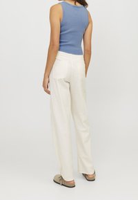 Světle modrý žebrovaný top bez rukávů v kombinaci se smetanovými kalhotami s širokými nohavicemi. Kalhoty mají dvě zadní kapsy a volný střih. Měkká textilie.