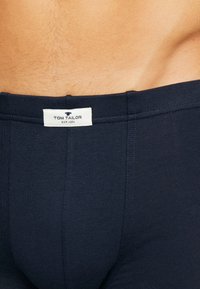 Boxeri din bumbac de culoare bleumarin, cu un talie moale. Prezintă un etichetă albă cu "TOM TAILOR EST. 1962" brodată pe spate.