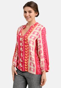 Long-sleeve shirt in pink and cream with floral and geometric patterns, featuring a V-neck, elastic cuffs, and a relaxed fit.