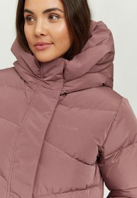 Padded jacket in soft mauve fabric with high collar, diagonal seam pattern, and subtle "MAZINE" branding on the chest.