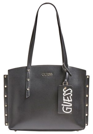 Sac cabas noir Guess avec longues anses, détails cloutés sur les côtés, logo en métal et étiquette de marque rectangulaire attachée.
