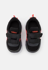 Černé sportovní boty s červenými akcenty, síťovaným svrškem, dvojitými suchými zipy, lehkým designem a bílými gumovými podrážkami.