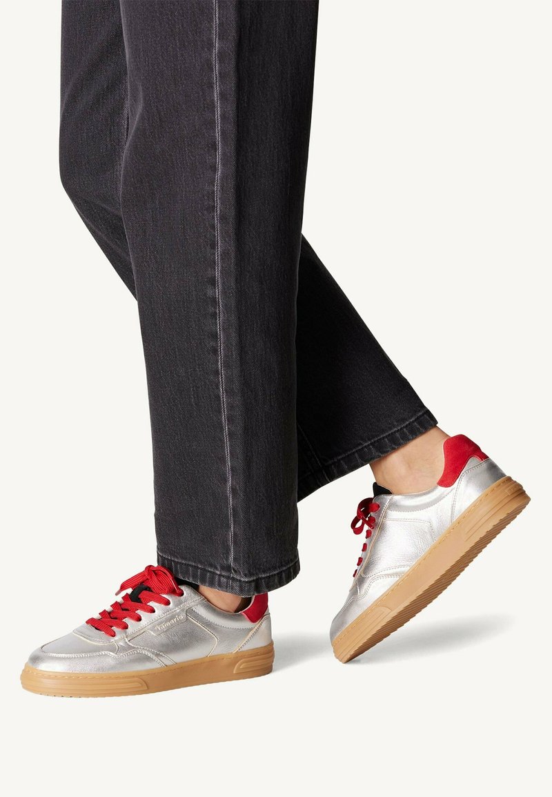 Sneakers argento con accenti rossi e dettagli neri. Presentano una tomaia texturizzata, chiusura con lacci e suola in gomma per una migliore trazione.