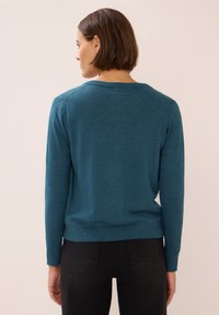 Teal, langslouchtrui met een ronde hals, geribde manchetten en zoom. Zachte textuur, eenvoudig ontwerp en aansluitende pasvorm.