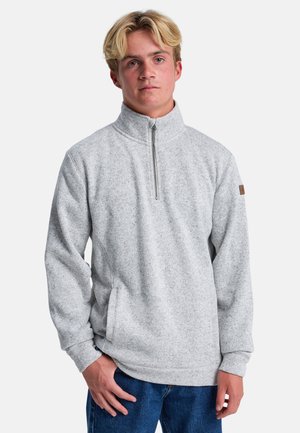 Sudadera de forro polar gris claro con cuello de medio zip, bolsillos laterales y un patrón texturizado. Presenta un pequeño parche marrón en la manga.