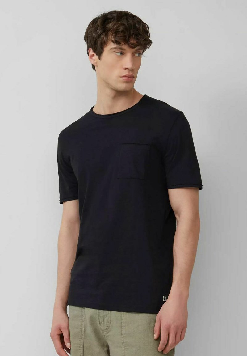 Black cotton t-shirt with short sleeves, round neckline, and a left chest pocket. Smooth texture and minimalistic design.