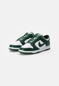 Zapatillas de cuero verdes y blancas con puntera perforada, cordones redondos y suela de goma con un patrón texturizado.