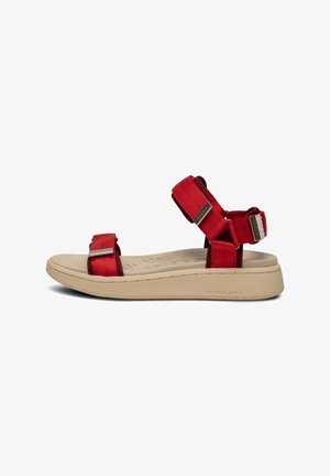 Red sandals with adjustable fabric straps and silver hardware. Cushioned beige footbed and lightweight, textured rubber sole.