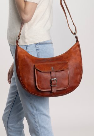 Sac à épaule en cuir brun avec une forme courbée, bandoulière réglable et poche avant à rabat avec une fermeture à boucle et des accents en métal.