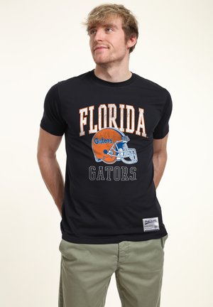 Black short-sleeve t-shirt featuring "Florida Gators" text in orange and white, with a blue football helmet graphic. Cotton material, standard fit.