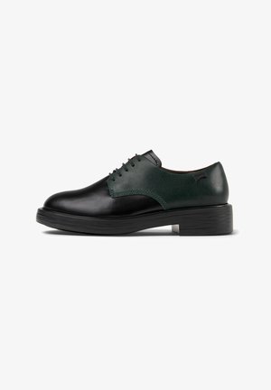 Chaussures en cuir noir avec un panneau supérieur en cuir vert, dotées d'un bout rond, d'un laçage et d'une épaisse semelle en caoutchouc noir.