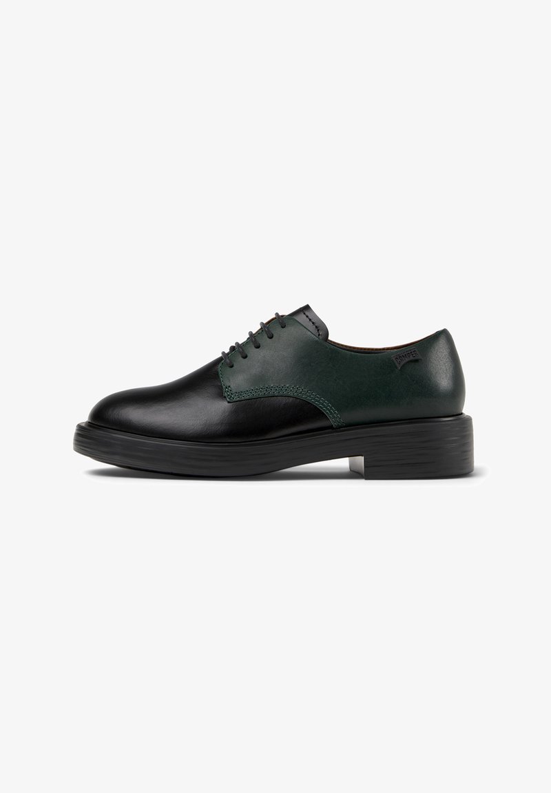 Scarpe in pelle nera con un pannello superiore in pelle verde, caratterizzate da una punta rotonda, un design con lacci e una spessa suola in gomma nera.