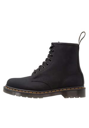 Schwarzer Schnür-Stiefelette mit gelber Naht auf dicker Gummisohle und Stoff-Schlaufe hinten.