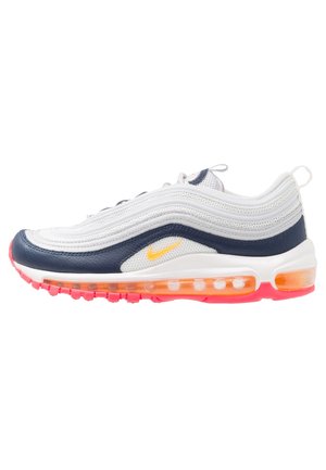 Tenisky Nike Air Max 97 mají bílou síťovinovou horní část s námořnickými koženými akcenty, oranžovou průhlednou podešví a žlutým logem. Zakřivený design se pruhovanou texturou.
