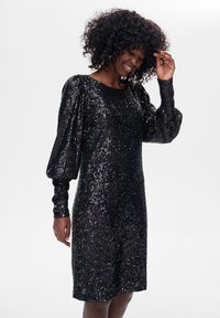 Czarna sukienka z cekinami, z okrągłym dekoltem, długimi bufiastymi rękawami i prostą sylwetką, o teksturowanej, refleksyjnej powierzchni.
